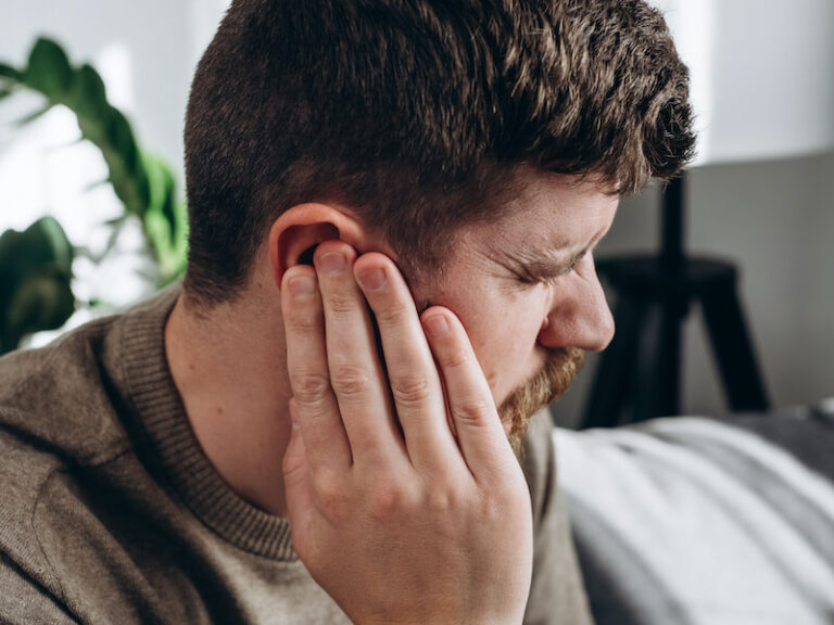 Man pressing ear annoyed with his tinnitus.