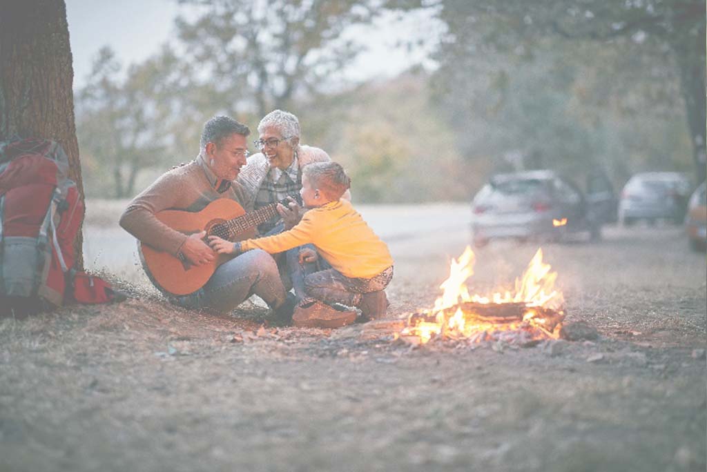 Family with a guitar around a campfire.