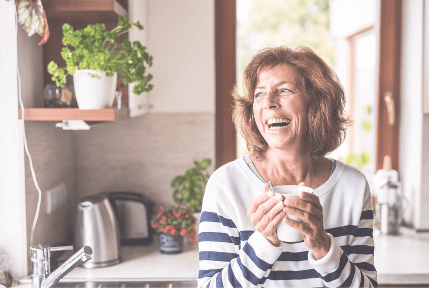 Mature woman smiling and holding a coffee